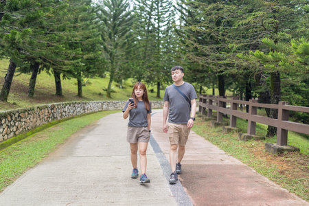 Chinese Malaysian couple in their 30s walking closely together in a lush, water-filled park in Kuala Lumpur, Malaysia.の写真素材