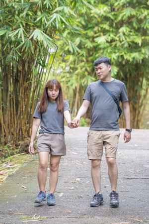 Chinese Malaysian couple in their 30s walking closely together in a lush, water-filled park in Kuala Lumpur, Malaysia.の写真素材
