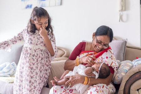 ndian family spending time together, wearing traditional and casual outfits with a baby, a young girl, and grandparents in a high-rise apartment in Kuala Lumpur, Malaysia.の写真素材