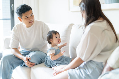 A 1 year old Taiwanese girl spending time playing happily with her parents, a man and woman in their 20s, in a room of a high rise apartment in Taichung City, Taiwan.の写真素材