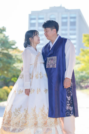 A Korean couple, a man in his 30s and a woman in her 20s, are seen wearing hanbok and looking at each other in a historic building in Seoul, South Korea.の写真素材