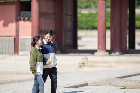 A sporty Korean couple, a man in his 30s and a woman in her 20s, wearing tracksuits, spends their time together happily at a historical building in Seoul, South Korea.の写真素材