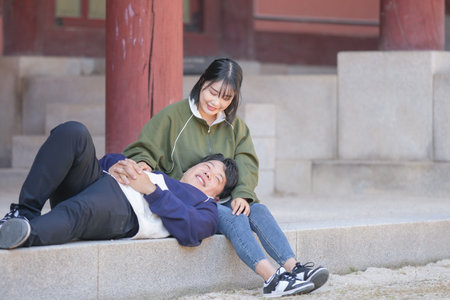 A sporty Korean couple, a man in his 30s and a woman in her 20s, wearing tracksuits, spends their time together happily at a historical building in Seoul, South Korea.の写真素材