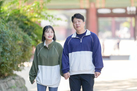 A Korean couple, a man in his 30s and a woman in her 20s, walks harmoniously through a historical building in Seoul, South Korea, wearing Hanbok.の写真素材