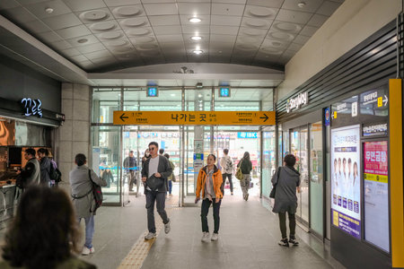 Group of people are walking through a train station. There are signs on the wall that say 7 and 4のeditorial素材