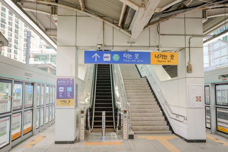 Train station with a blue sign that says "ATM" on it. There is a staircase leading up to the train platformのeditorial素材