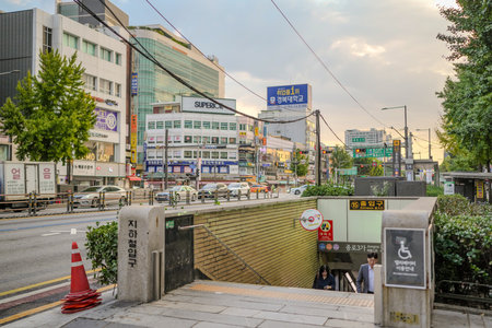 Man is walking down a subway entrance. The sign is in a foreign language. There are many cars on the streetのeditorial素材