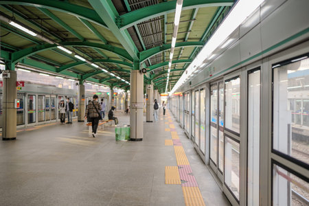 Train station with a few people walking around. There are two benches and a trash canのeditorial素材