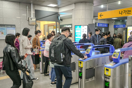 Group of people are standing in line at a train station. There are several people with backpacks and handbagsのeditorial素材