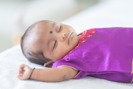 An Indian family wearing traditional and casual costumes spends time with their baby, girl and...