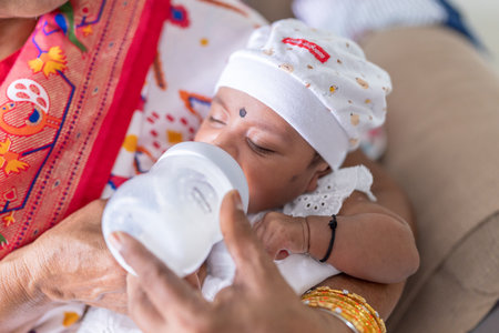 An Indian family wearing traditional and casual costumes spends time with their baby, girl and...