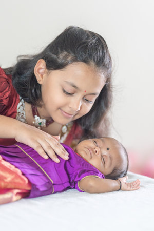 An Indian family wearing traditional and casual costumes spends time with their baby, girl and...