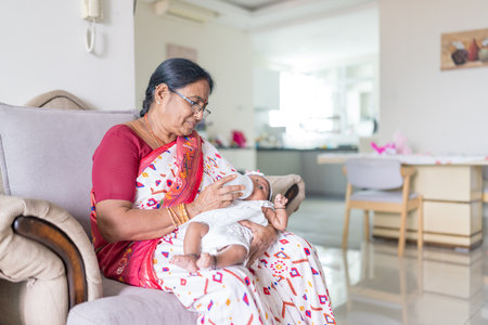 An Indian family wearing traditional and casual costumes spends time with their baby, girl and grandparents in a high-rise apartment building in Kuala Lumpur, Malaysia. June 2024の写真素材