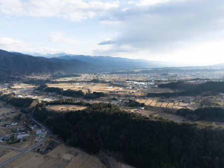 Aerial photograph of the countryside, including rice and private houses, including snow-covered Mt. Senjogatake and Mt. Kiso-Komagatake in Komagane City, Nagano Prefecture, Japan in winter.の写真素材