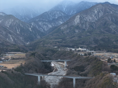 Aerial photograph of the countryside, including rice and private houses, including snow-covered Mt. Senjogatake and Mt. Kiso-Komagatake in Komagane City, Nagano Prefecture, Japan in winter.の写真素材