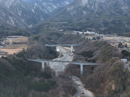 Aerial photograph of the countryside, including rice and private houses, including snow-covered Mt. Senjogatake and Mt. Kiso-Komagatake in Komagane City, Nagano Prefecture, Japan in winter.の写真素材