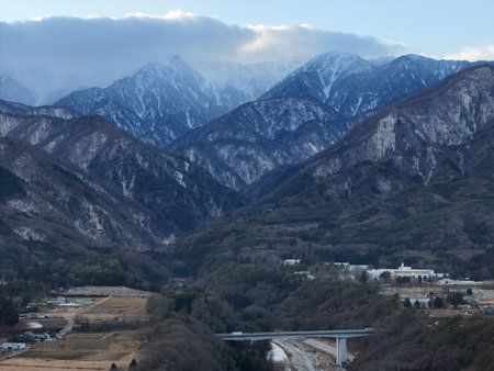 Aerial photograph of the countryside, including snow-covered Mt. Senjogatake and Mt. Kiso-Komagatake in Komagane City, Nagano Prefecture, Japan in winter.の写真素材