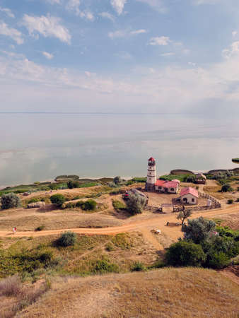 views of the hilly plain and the sea. Summer landscape, high hilly banks. Wonderful sea view and mountain spring landscape. A picturesque hilly coastline, an old lighthouse, roads for cars and people. Lighthouse keeper's house. Copy space with space for textの写真素材