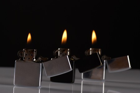 Three lit gasoline lighters standing in a rowの写真素材