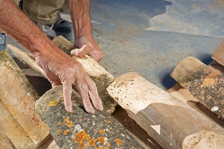 Construction worker repairing a roof with clay tilesの写真素材