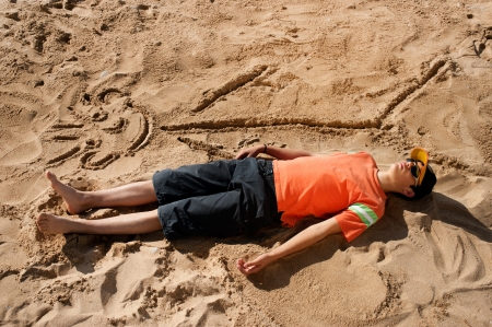 Artistic teenager sunbathing next to his beach cartoonの写真素材