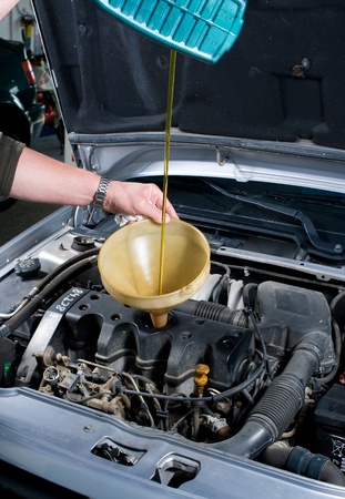 Car mechanic filling fresh oil into an engineの写真素材