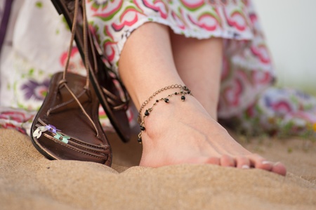 Female feet and leather sandals on a sandy dune in springの写真素材