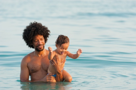 Baby girl enjoying her first day on the beach together with dadの写真素材