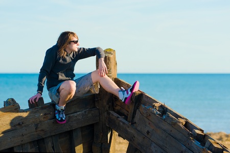 Teenager sitting on the prow of a shipwreck, a conceptの写真素材