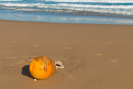 Old buoy washed up on a sunny sand beachの写真素材