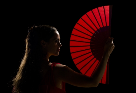Female dancer holding a backlit red folding fanの写真素材