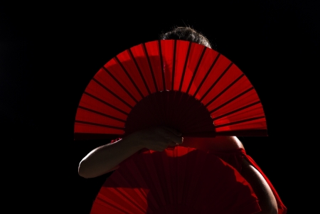 Female flamenco performer hidden behind her folding fansの写真素材