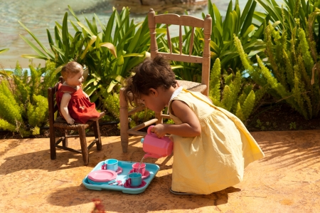 Little girl and her vintage doll playing tea time in a parkの写真素材