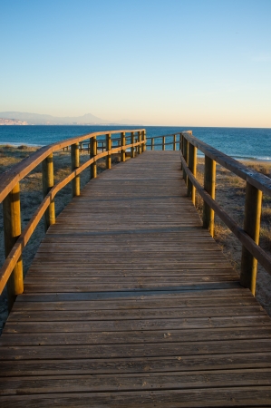 Footbridge leading towards a sunny Mediterranean beachの写真素材