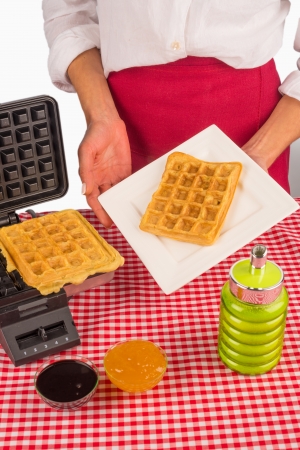 Ready to eat waffles next to the waffle ironの写真素材