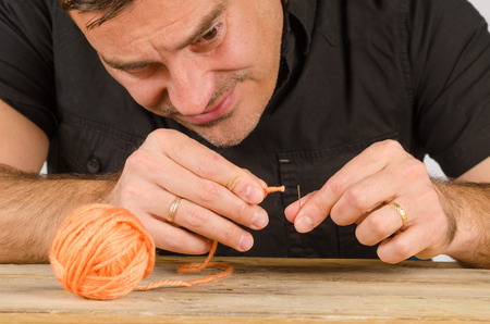 Guy having a hard time with needle and thread