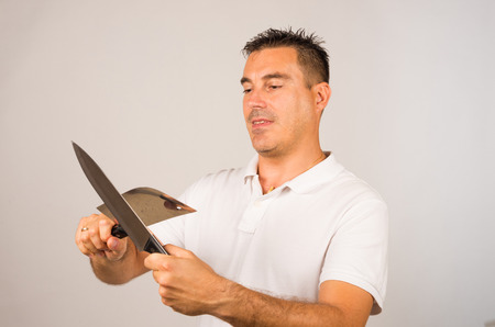 Man whetting a kitchen knife and an axe