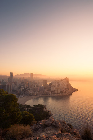 A foggy early morning casting its light on Benidorm skylineの写真素材