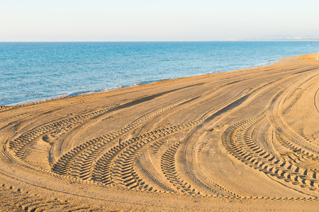 Fresh tyre tracks on a sunny Mediterranean beachの写真素材