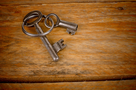 Old keys and key ring on a wooden background