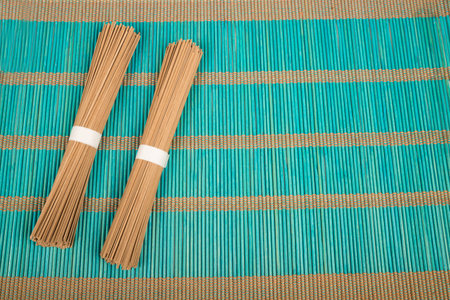Two bundles of soba on  a bamboo mat