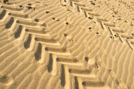 Many tyre tracks and footprints on sand
