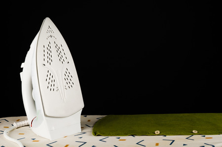 Steam iron on an ironing board next to a shirtの写真素材