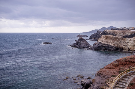 Volcanic coastline under a moody storm skyの写真素材
