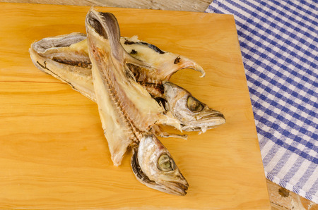 Two dried and salt cured whitings on a chopping board