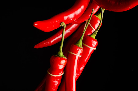 Bundle of hot chili peppers on a black backgroundの写真素材