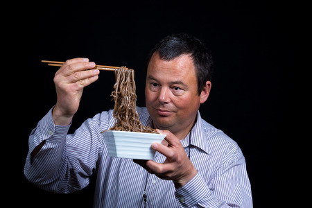 Guy experiencing how difficult it can be to eat with chopsticks