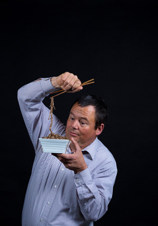 Eating with chopsticks, quite a challenge for this guyの写真素材