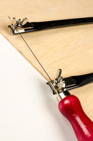 Small fretsaw on a board of plywoodの写真素材