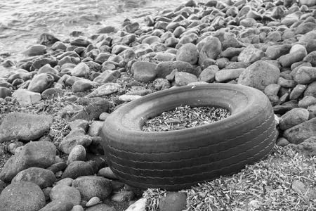 Old vehicle tyre washed ashore on a pebbled beachの写真素材